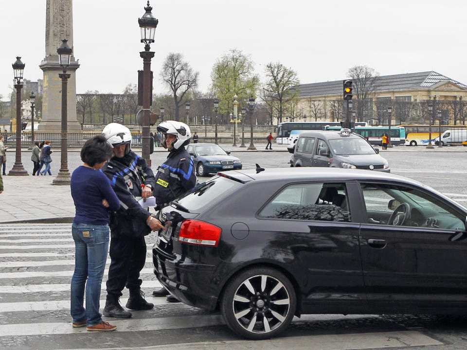 Police officers control a vehicle on the Concorde square in Paris, Monday, March 17, 2014. Cars with even-numbered license plates are prohibited from driving in Paris and its suburbs Monday, following a government decision over the weekend. Paris is taking drastic measures to combat its worst air pollution in years, banning around half of the city's cars and trucks from its streets in an attempt to reduce the toxic smog that's shrouded the City of Light for more than a week. (AP Photo/Remy de la Mauviniere)