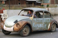 <p>An ethnic Albanian steers a decrepit car his family has salvaged as it is towed down a street in the provincial Kosovo capital, Pristina, on Sept. 21, 1999. (Photo: Jacqueline Larma/AP) </p>