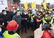 In this photo released by China's Xinhua News Agency, Chinese Premier Li Keqiang, fourth left, speaks with construction workers at the site of makeshit field hospital being built in Wuhan in central China's Hubei province, Monday, Jan. 27, 2020. China on Monday expanded its sweeping efforts to contain a deadly virus, extending the Lunar New Year holiday to keep the public at home and avoid spreading infection. (Li Tao/Xinhua via AP)