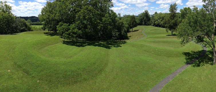 Grassy earthworks in a field with trees