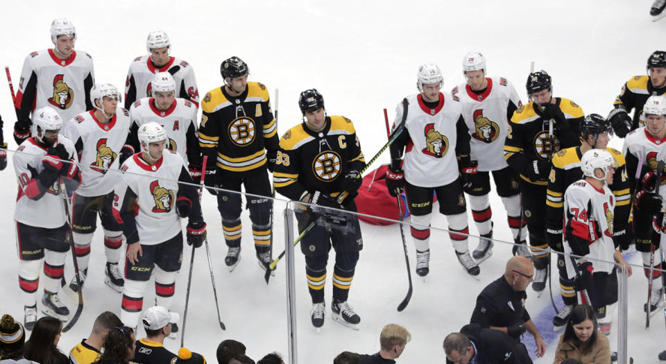 Members of the Ottawa Senators and Boston Bruins watch as medical workers attend to Senators forward Scott Sabourin, who was injured following a collision with Bruins' forward David Backes on Saturday night. (AP Photo/Charles Krupa)