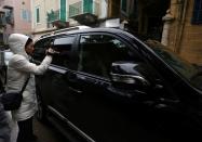 A journalist carries a camera near a car outside the house believed to belong to former Nissan chairman Carlos Ghosn in Beirut