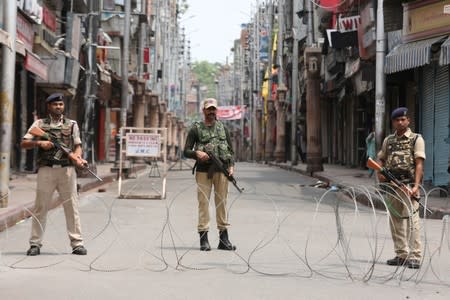 Indian security personnel stand guard along a deserted street during restrictions in Jammu