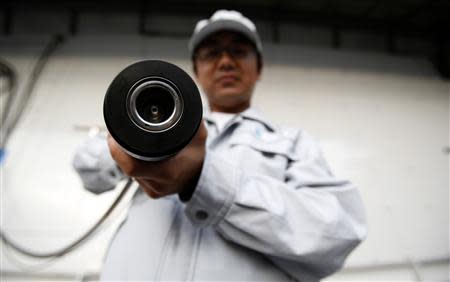 A staff member of Taiyo Nippon Sanso holds a hydrogen nozzle during a photo opportunity at the Toyota Advanced Technologies media briefing in Tokyo in this October 10, 2013 file photo. REUTERS/Yuya Shino/Files