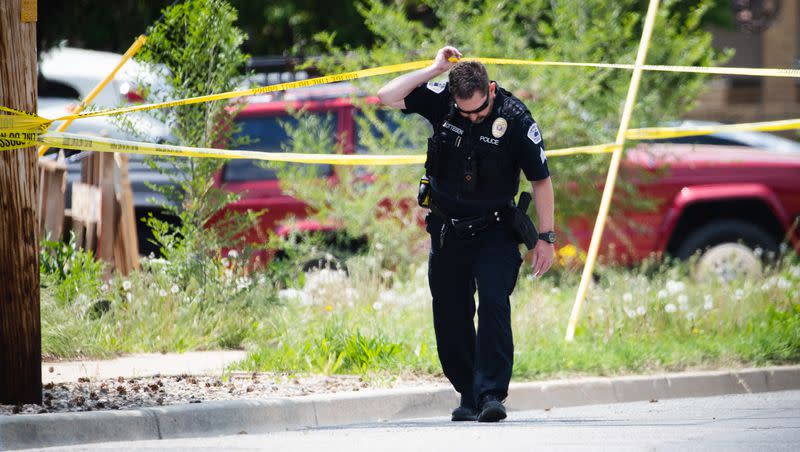 A Layton Police officer crosses police tape at the scene of a triple homicide in Layton on Friday, May 19, 2023.