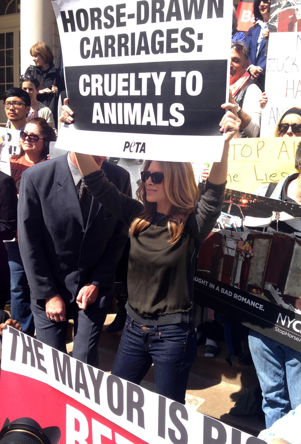 Jillian Michaels, from "The Biggest Loser," holds up a sign on City Hall steps at a PETA-sponsored rally protesting horse carriages, in New York. The mayor, Bill de Blasio, also supports banning the carriages. (AP Photo/Jonathan Lemire)