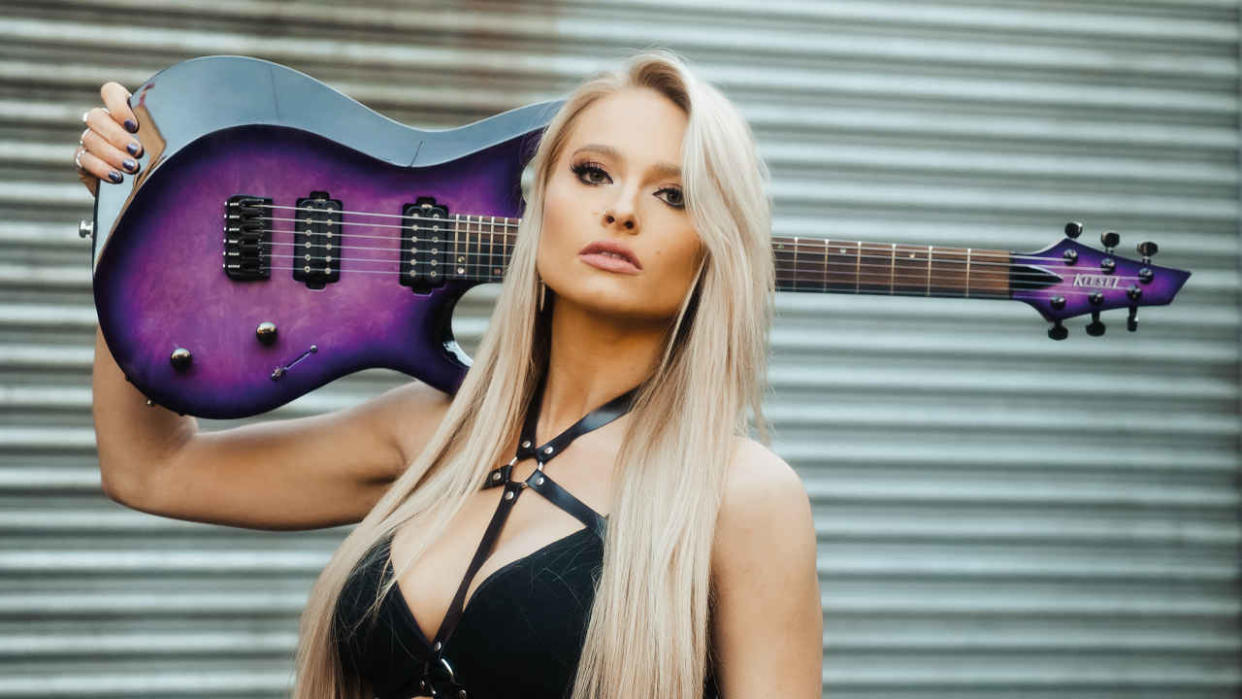  Sophie Lloyd holdimg a guitar over her shoulder. 