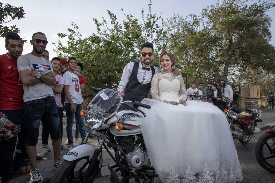 FILE - In this April 16, 2020 file photo, newlyweds are surrounded by their friends as they celebrate before a curfew imposed as a prevention measure against the coronavirus pandemic, in Cairo, Egypt. In a region where marriage is the cornerstone of society, couples are plowing ahead with weddings, despite the deadly risks. From the Palestinian territories to the United Arab Emirates, officials attribute a spike in coronavirus cases to traditional, large-scale weddings that flout public health restrictions. (AP Photo/Nariman El-Mofty, File)