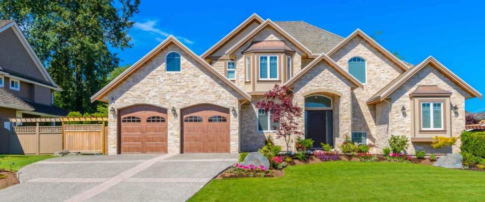 Big custom made luxury house with nicely landscaped front yard and driveway to garage in the suburbs of Vancouver, Canada.