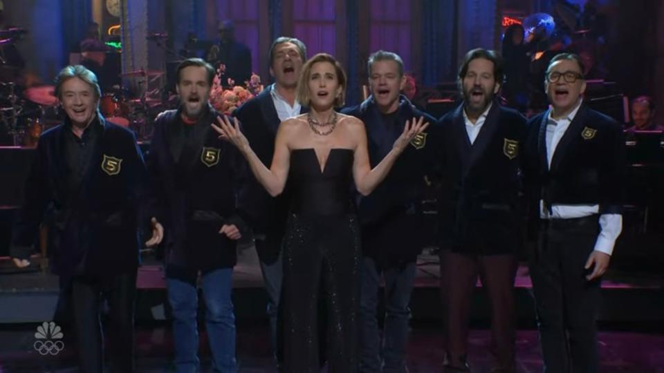 Exasperated, Wiig turns to Michaels and demands an explanation but finds that the “SNL” head honcho is surrounded by Jon Hamm, Fred Armisen, Will Forte, and Martin Short — all donning jackets despite not hosting five times. NBC / SNL