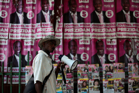 A street vendor walks past electoral posters of presidential candidate Jovenel Moise, of PHTK (Bald Head Haitian Party), along a street of Port-au-Prince, Haiti, November 16, 2016. REUTERS/Andres Martinez Casares