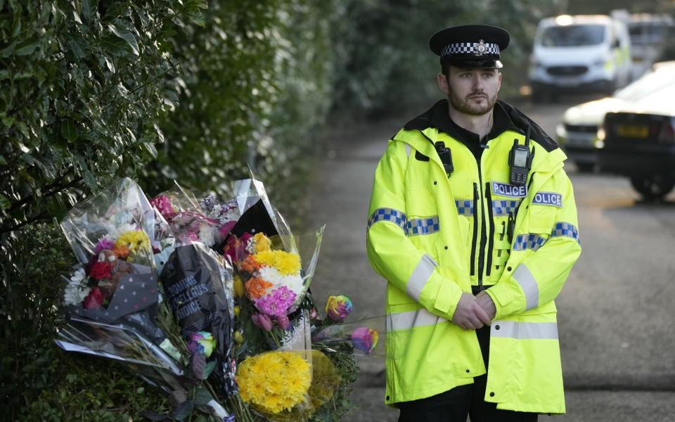 A police officer stands next to floral tributes at the entrance toLinear Park - Christopher Furlong