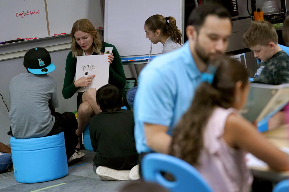 Karly LaOrange, lead teacher for a team of fourth and fifth grade classes at Whittier Elementary School interacts with students, Tuesday, Oct. 18, 2022 in Mesa, Ariz. Like many school districts across the country, Mesa has a teacher shortage due in part due to low morale and declining interest in the profession. Five years ago, Mesa allowed Whittier to participate in a program making it easier for the district to fill staffing gaps, grant educators greater agency over their work and make teaching a more attractive career. The model, known as team teaching, allows teachers to combine classes and grades rotating between big group instruction, one-on-one interventions, small study groups or whatever the team agrees is a priority each day. (AP Photo/Matt York)