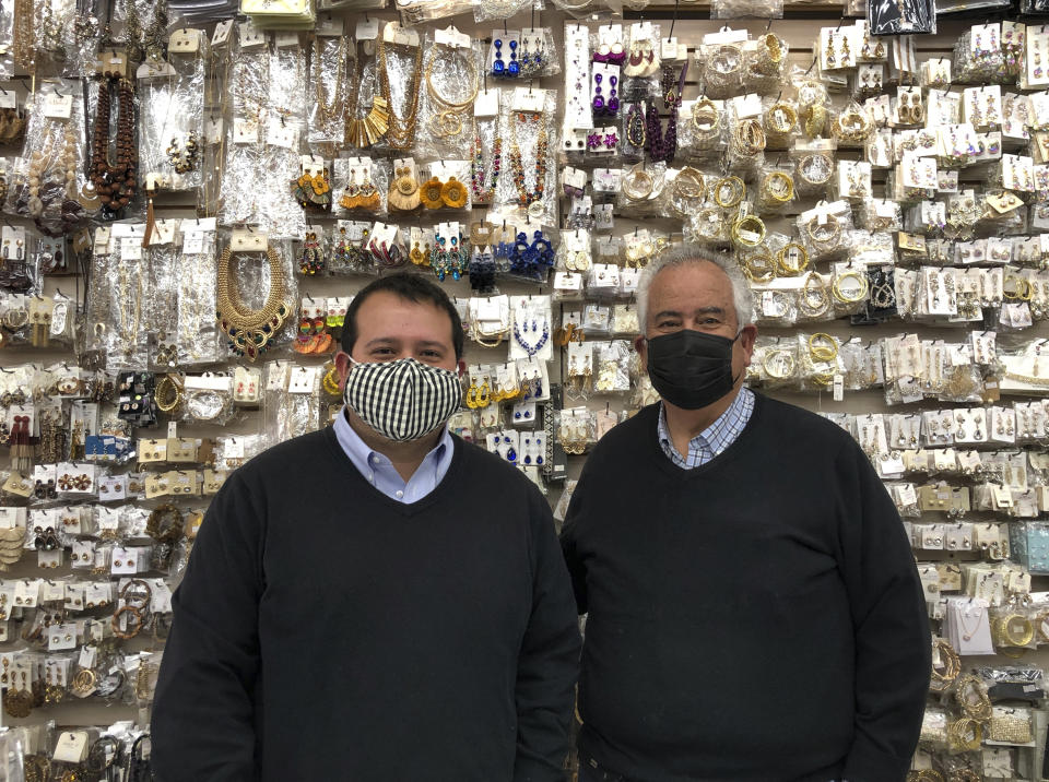 Business owner Greg Kory and his father stand in front of a wall of jewelry at their downtown Nogales, Arizona, store on March 15, 2021. Two of the family's three clothing stores located steps away from the U.S.-Mexico border have been closed for almost a year, with their main customer base, Mexican day-trippers, largely unable to come to the U.S. and shop due to the partial closure of North America's international boundaries during the pandemic. (AP Photo/Suman Naishadham)