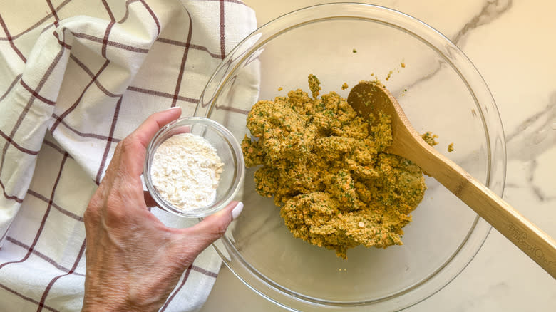 hand adding flour to bowl