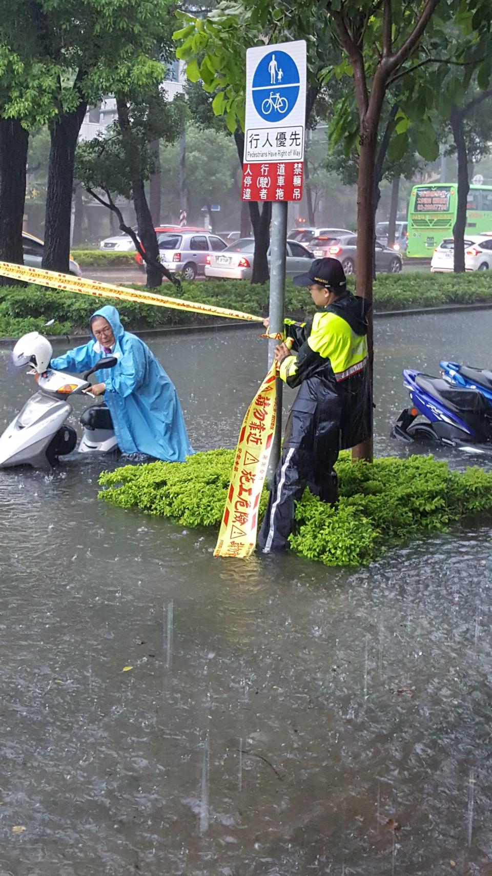 高雄市23日瞬間強降雨不斷，造成多處積水盈尺，路上多部汽機車拋錨，交通打結，圖為新興區民生路淹水一景。（中央社/警方提供）