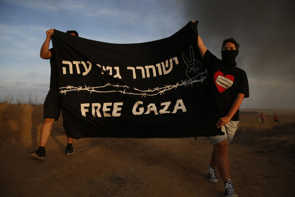 Israeli peace activists hold a banner during a protest on Israel Gaza border, Friday, Oct. 5, 2018. Writing in Hebrew reads "Free Gaza ghetto". (AP Photo/Ariel Schalit)