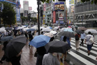 Morning commuters with umbrella cover a crosswalk Tuesday, July 27, 2021, in Tokyo. The rains have come to Tokyo and its Olympics. After many days of blistering sunshine, the rain cooled Tokyo by about 10 degrees and took the edge off. But worries about the effect of Tropical Storm Nepartak have led to changes in events and some cancellations of practices as preparations proceed. The storm is expected to make landfall in Japan on Tuesday evening. (AP Photo/Kiichiro Sato)