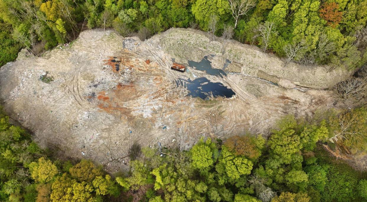 An aerial image of the waste tipped into Hoads Wood with a vast area of waste sat surrounded by green trees