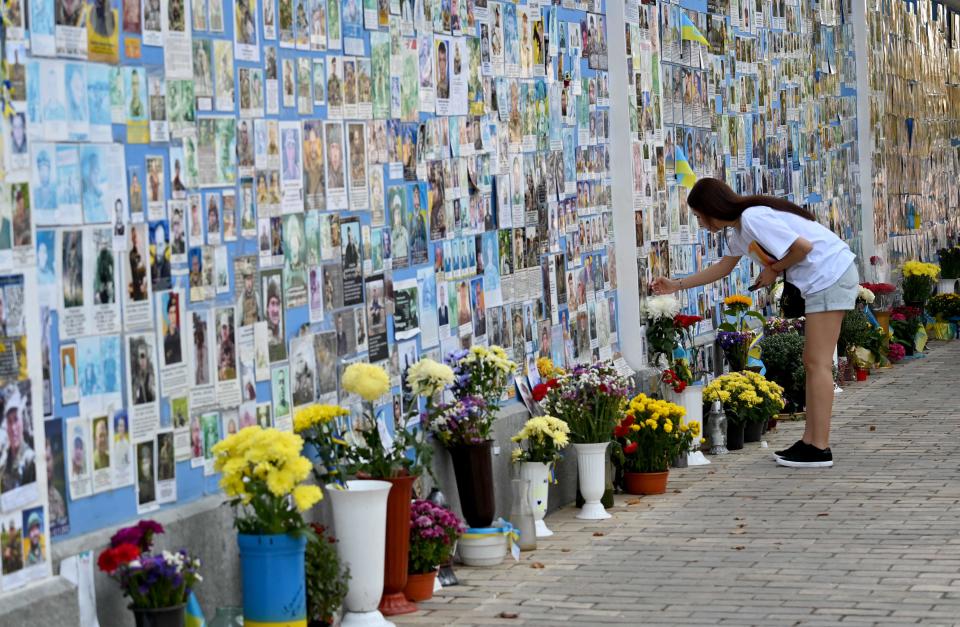 A girl touches a photograph of her relative on the Memory Wall of Fallen Defenders of Ukraine (AFP via Getty Images)