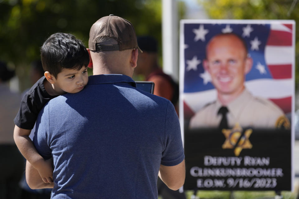 A supporter takes photos of a shrine to Los Angeles County sheriff's deputy Ryan Clinkunbroomer outside of the Palmdale Sheriff's Station Monday, Sept. 18, 2023, in Palmdale, Calif. Deputy Clinkunbroomer was shot and killed while sitting in his patrol car Saturday evening in Palmdale. (AP Photo/Marcio Jose Sanchez)