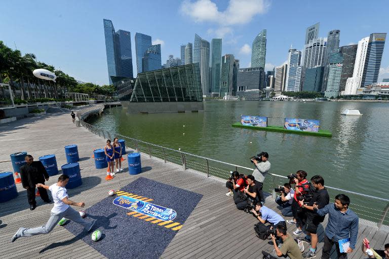 Fabio Cannavaro (L), former Italian football captain, kicks the ball towards the water during a promotional event for Tiger Street Football in Singapore on October 17, 2013