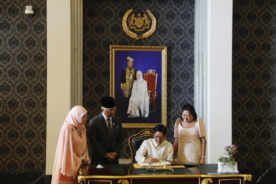 CORRECTS THE PHOTOGRAPHER'S LAST NAME TO ISMAIL, NOT ISMAL - Philippine President Ferdinand Marcos Jr., second from right, signs a guest book while Malaysia's King Sultan Abdullah Sultan Ahmad Shah, second from left, Malaysia's Queen Azizah Aminah Maimunah, left, and first lady Maria Louise Araneta Marcos look on during the state welcome ceremony at National Palace in Kuala Lumpur, Malaysia, Wednesday, July 26, 2023. (Fazry Ismail/Pool Photo via AP)