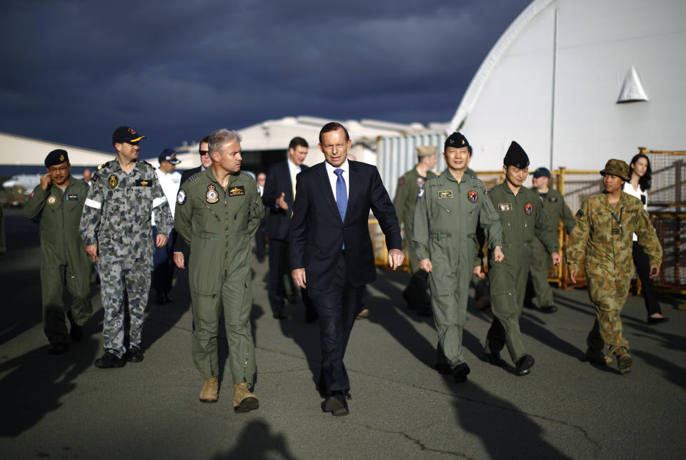 El primer ministro australiano Tony Abbott camina con el jefe del Grupo de la Fuerza Aérea de Australia Craig Heap (tercero desde la izquierda) y líderes de fuerzas militares internacionales destacadas en Perth, durante la visita de Abbott a la Base Pearce de la Fuerza Aérea Australiana cerca de Perth, el lunes 31 de marzo de 2014. (Foto AP/Jason Reed, Pool)
