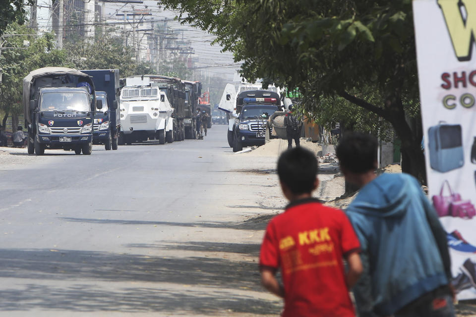 People watch as a row of vehicles by security forces are parked on a road in Mandalay, Myanmar Friday, March 19, 2021. The authorities in Myanmar have arrested a spokesman for ousted leader Aung San Suu Kyi's political party as efforts to restrict information about protests against last month's military takeover are tightened. (AP Photos)