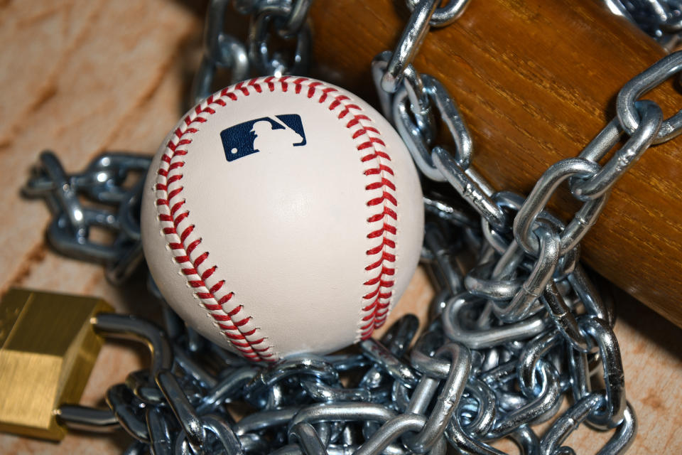 Brownsburg, IN - December 2: An Official Rawlings Major League Baseball sits with a bat, lock and chain to represent the lockout between Major League Baseball (MLB) and the Major League Baseball Players Association (MLBPA) on December 2, 2021 in Brownsburg, IN. (Photo by James Black/Icon Sportswire via Getty Images)