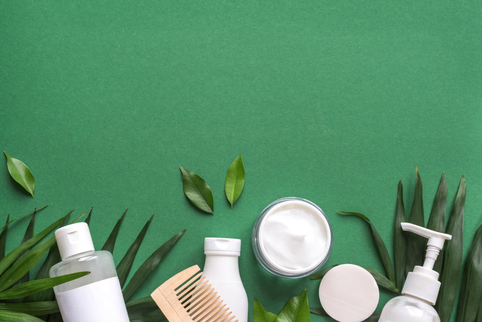 Organic Hair Care products with green leaves on green background, trendy layout, eco beauty and healthy lifestyle concept.