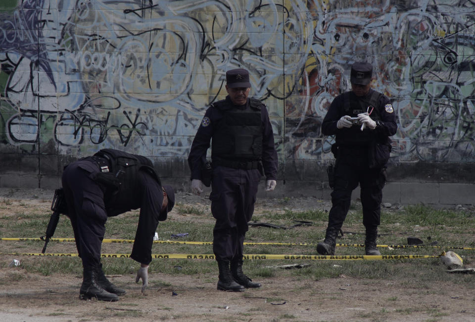 Police investigate the field where a car exploded as authorities were responding to a report of a vehicle with a corpse inside, in the San Bartolo neighborhood of Soyapango, El Salvador, Monday, April 29, 2019. Two police officers were injured in the explosion. (AP Photo/Salvador Melendez)