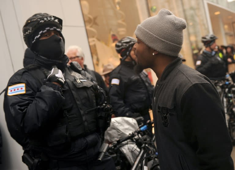 Protester Jared Steverson confronts a police officer guarding a store on November 27, 2015 as demonstrations disrupt shopping on Chicago's Magnificent Mile to demand justice for a black teen killed by a police officer in 2014