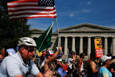 A policeman on a bicycle passes supporters of U.S. Senator Bernie Sanders as they take part in a protest march ahead of the 2016 Democratic National Convention in Philadelphia, Pennsylvania on July 24, 2016. REUTERS/Adrees Latif