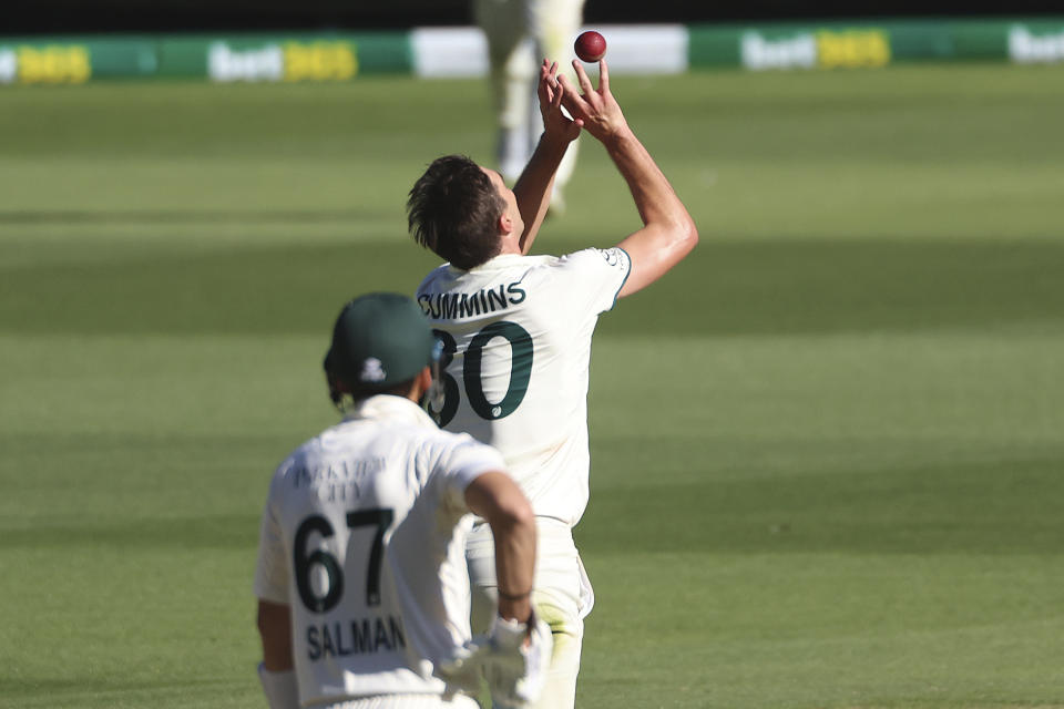 Australia's Pat Cummins grabs the ball to complete a caught-and-bowled dismissal of Pakistan's Aamer Jamal during the fourth day of their cricket test match in Melbourne, Friday, Dec. 29, 2023. (AP Photo/Asanka Brendon Ratnayake)