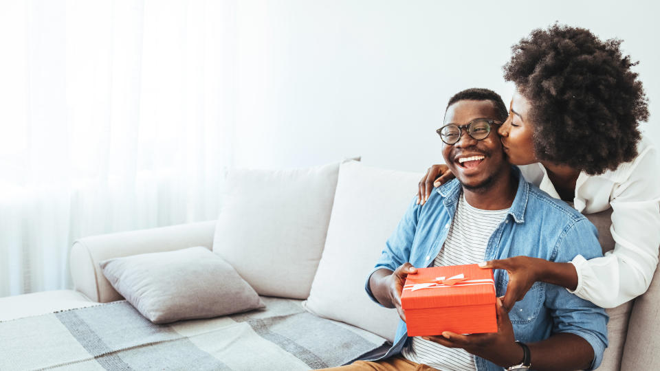 Young couple with gift box hugging at home. Valentine's Day concept. Happy couple in love with. A young loving couple celebrating Valentine's Day at the home. Lovers give each other gifts. Romance home for Valentine's Day- concept