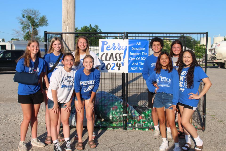 Members of the Perry Class of 2024 pose for a photo with the can collection cage at the Diamond Oil parking lot, located 808 2nd St.