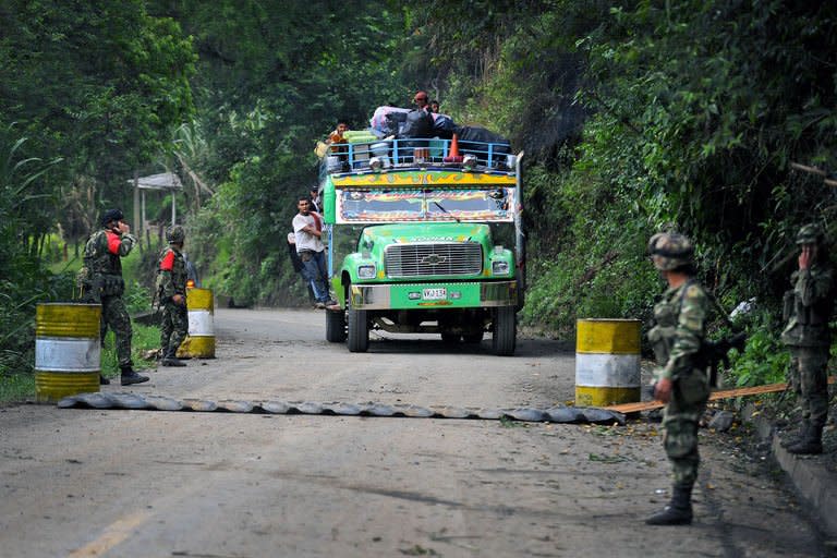 A "chiva" (public transportation) passes a checkpoint in El Palo, department of Cauca, Colombia, on February 5, 2013, after car bombs planted by FARC exploded