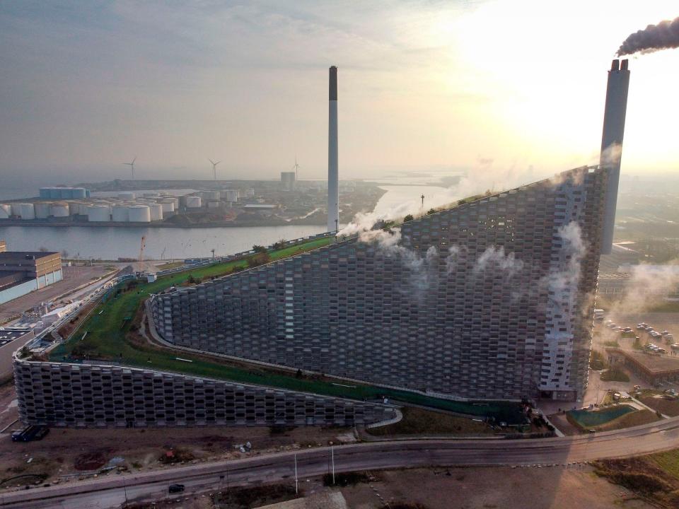 A photo of CopenHill, a large building in the shape of a right angle triangle, with a climbing wall and smokestack.