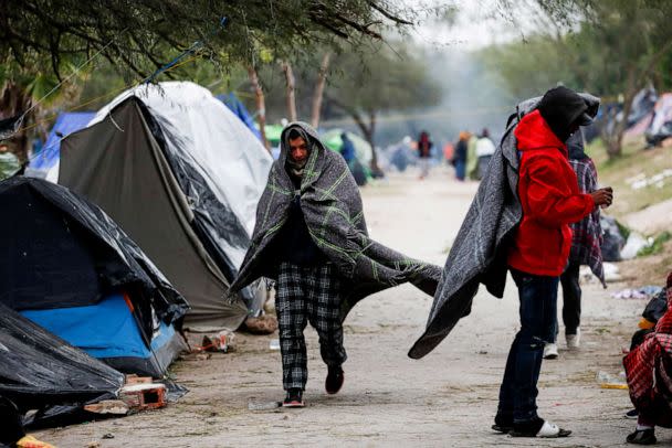 PHOTO: An asylum-seeking migrant walks covered with a blanket during a day of high winds and low temperatures at a makeshift encampment near the border between the U.S. and Mexico. (Daniel Becerril/Reuters)