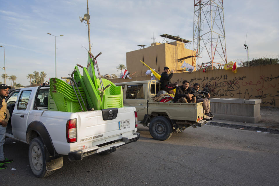 Pro-Iranian militiamen and their supporters board trucks loaded with items from a sit-in while driving away from the U.S. Embassy, in Baghdad, Iraq, Wednesday, Jan. 1, 2020. U.S. troops fired tear gas on Wednesday to disperse pro-Iran protesters who were gathered outside the U.S. Embassy compound in Baghdad for a second day. (AP Photo/Nasser Nasser)