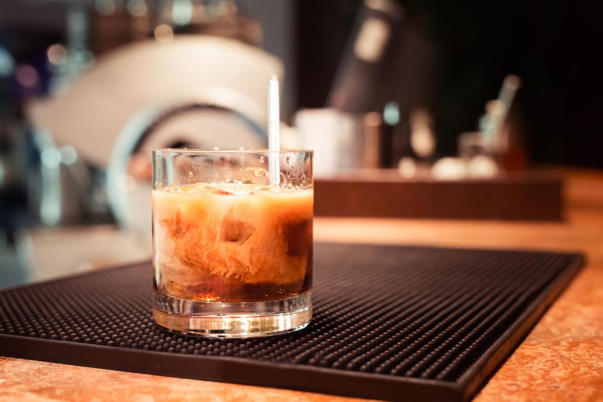 White russian cocktail on the bar stand on rubber mat. Shallow DOF and marsala tonned