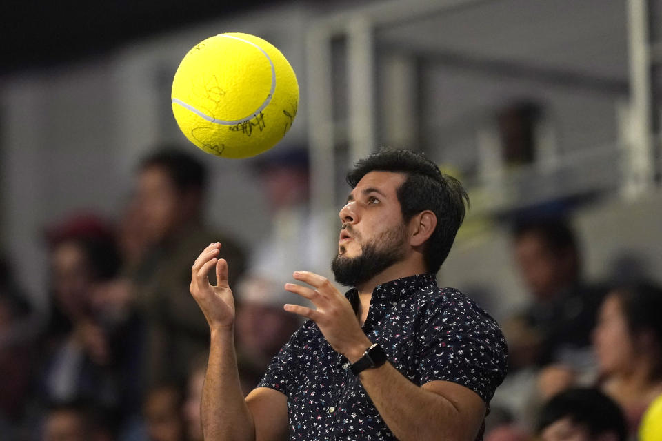 A fan in stands tosses a giant tennis ball during a break in the match between Iga Swiatek of Poland Coco and Gauff of the United States during round-robin play on day six of the WTA Finals tennis tournament in Fort Worth, Texas, Saturday, Nov. 5, 2022. (AP Photo/LM Otero)