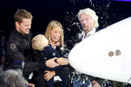 Richard Branson (R) stands with his son Sam (L) and daughter-in-law Isabella (2nd R) as he watches his one-year-old granddaughter Eva-Deia (2nd L) break a milk bottle to dedicate the new Space Ship Two, a six-passenger two-pilot vehicle meant to ferry people into space, that replaces a rocket destroyed during a test flight in October 2014, in Mojave, California, United States, February 19, 2016. REUTERS/Lucy Nicholson