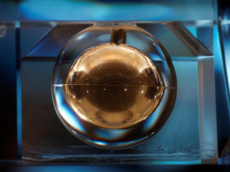 shiny golden orb with tiny rocks inside hangs in a blue box on display