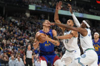 Denver Nuggets forward Michael Porter Jr., left, is blocked on the way to the basket by Minnesota Timberwolves center Rudy Gobert and forward Jaden McDaniels, right, in the first half of an NBA basketball game Friday, March 29, 2024, in Denver. (AP Photo/David Zalubowski)