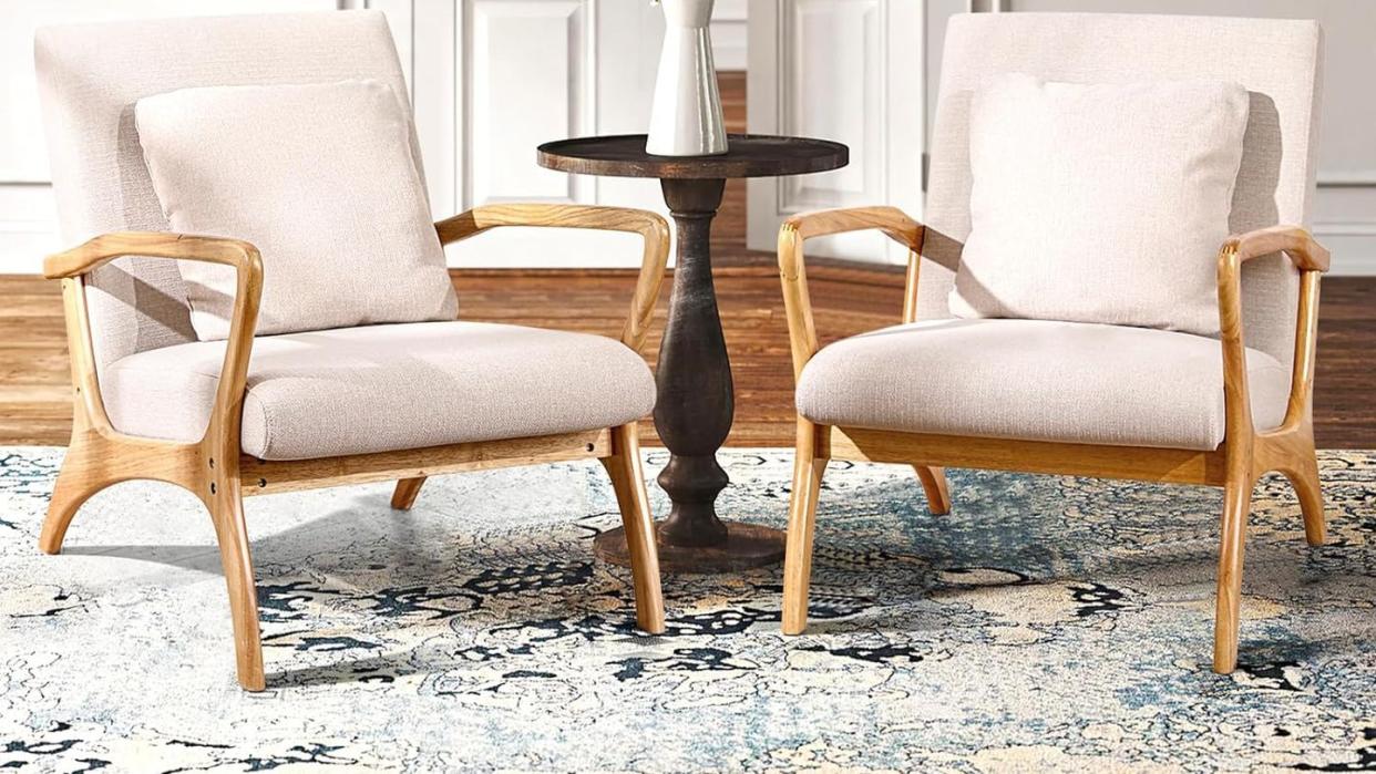 a couple of white chairs in a room with a table and a vase with flowers