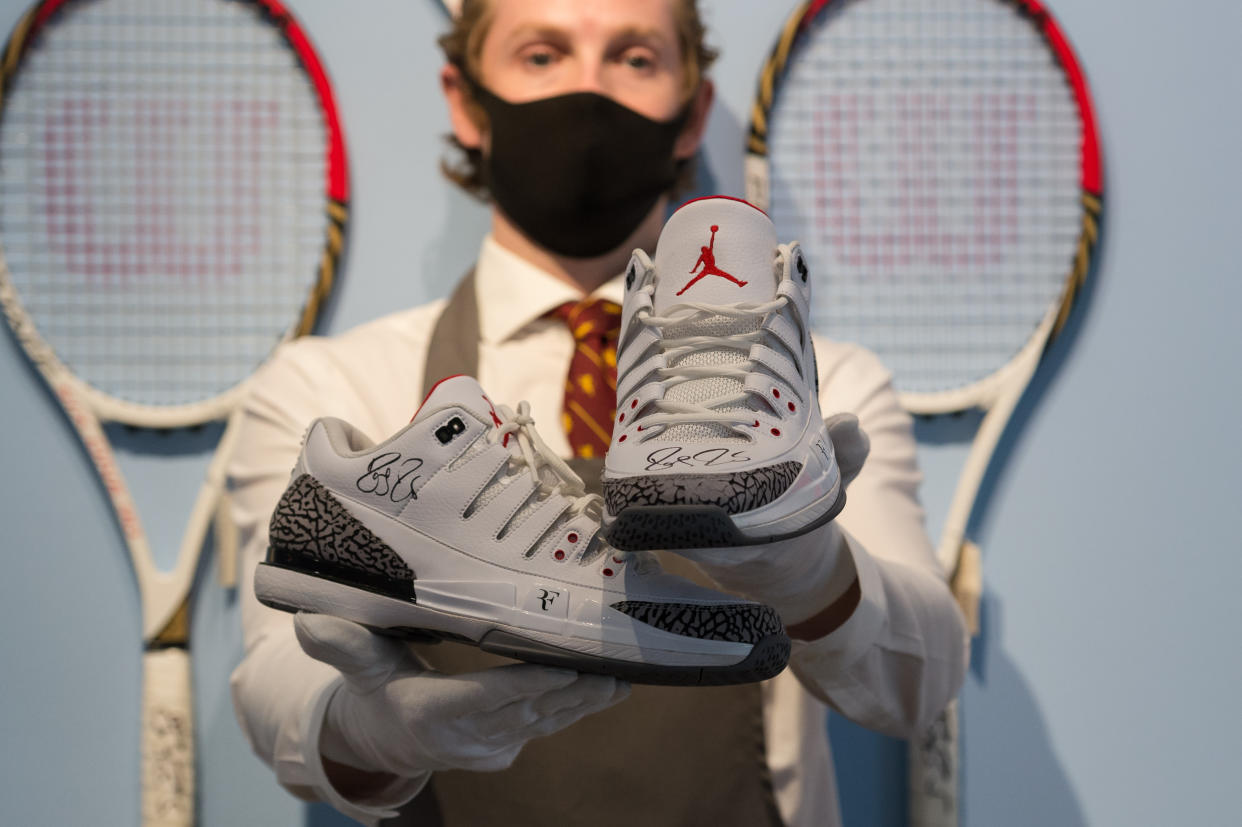 A staff member holds Roger Federer's signed tournament Air Jordans from 2014 US Open (est. Â£40,000-60,000)) during a photo call for 'The Roger Federer Collection: Sold to Benefit The RF Foundation' Evening and Online Sale at Christie's auction house in London, United Kingdom on June 21, 2021. (Photo by Wiktor Szymanowicz/Anadolu Agency via Getty Images)