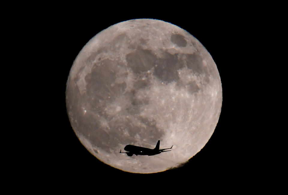 A passenger plane, with the moon seen behind, makes its final landing approach towards Heathrow Airport in London. (Photo: Toby Melville / Reuters)