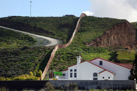 A house stands next to a section of the border fence separating Mexico and the United States, in Tijuana, Mexico. REUTERS/Edgard Garrido